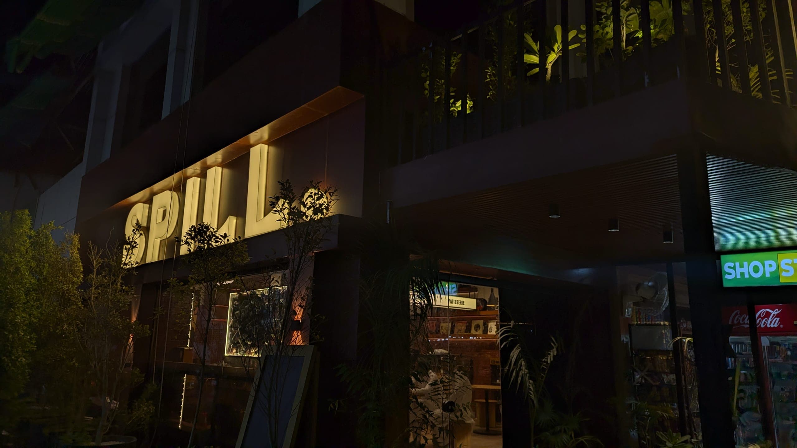 The Spill storefront glowing brass at night, next to the High Court in Bahawalpur